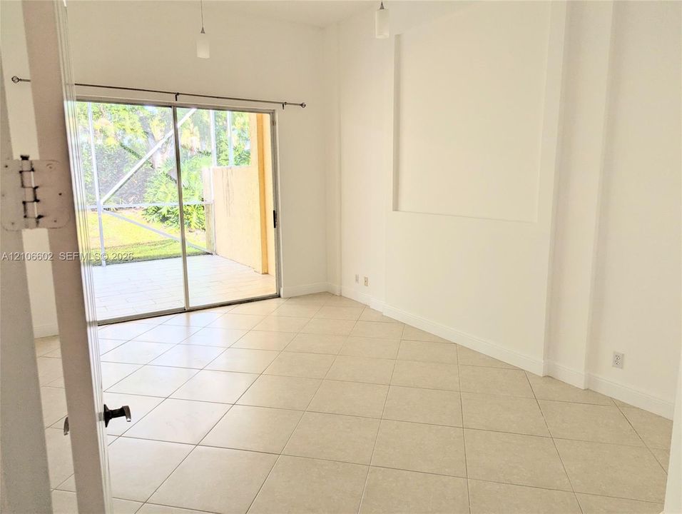 Interior space featuring large-format ceramic tile flooring, a recessed wall niche, sliding glass doors, and pendant lighting