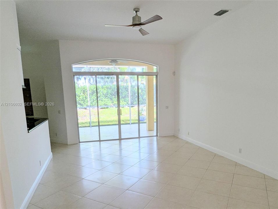 Interior space featuring vaulted ceilings, neutral tile flooring, a multi-blade ceiling fan, and arched sliding glass doors opening to a screened-in lanai