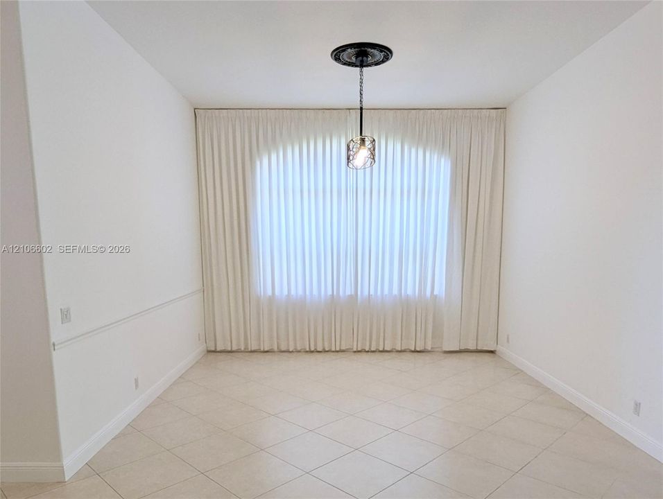 Arched window featuring full-length drapery, tile flooring, crown molding, and a ceiling-mounted pendant light with an ornate decorative medallion