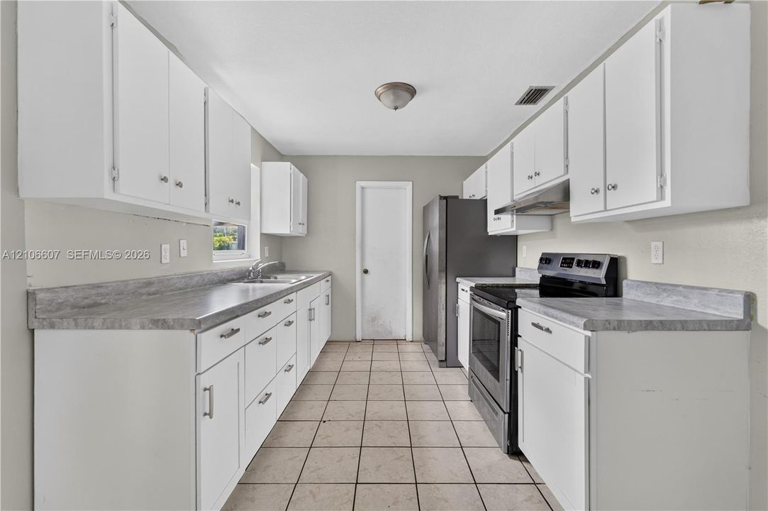 Kitchen featuring white cabinetry, stone-finish countertops, stainless steel appliances, and ceramic tile flooring