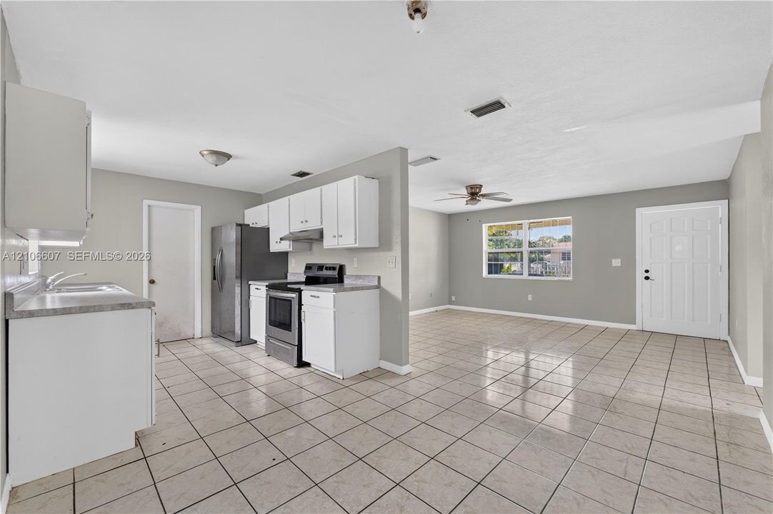 Kitchen featuring white cabinetry, stainless steel refrigerator and range, tile flooring, and a window with natural light