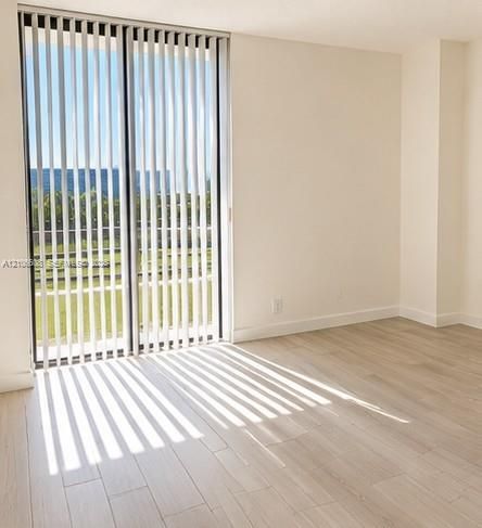 Floor-to-ceiling sliding glass doors with vertical blinds, light-toned wood-finish flooring, and neutral wall color