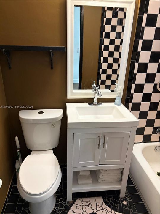 White vanity with a rectangular sink, wall-mounted mirror with a white frame, checkerboard tile surround, and built-in shelving