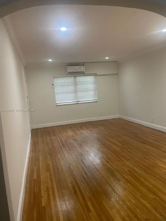 Interior space featuring wood-finish flooring, recessed lighting, and a wall-mounted climate control unit