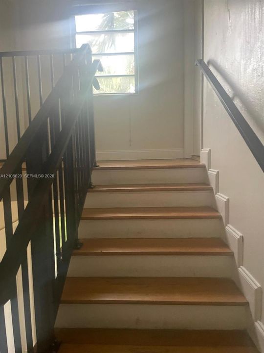Staircase featuring wood-finish treads, white risers, and black metal handrails