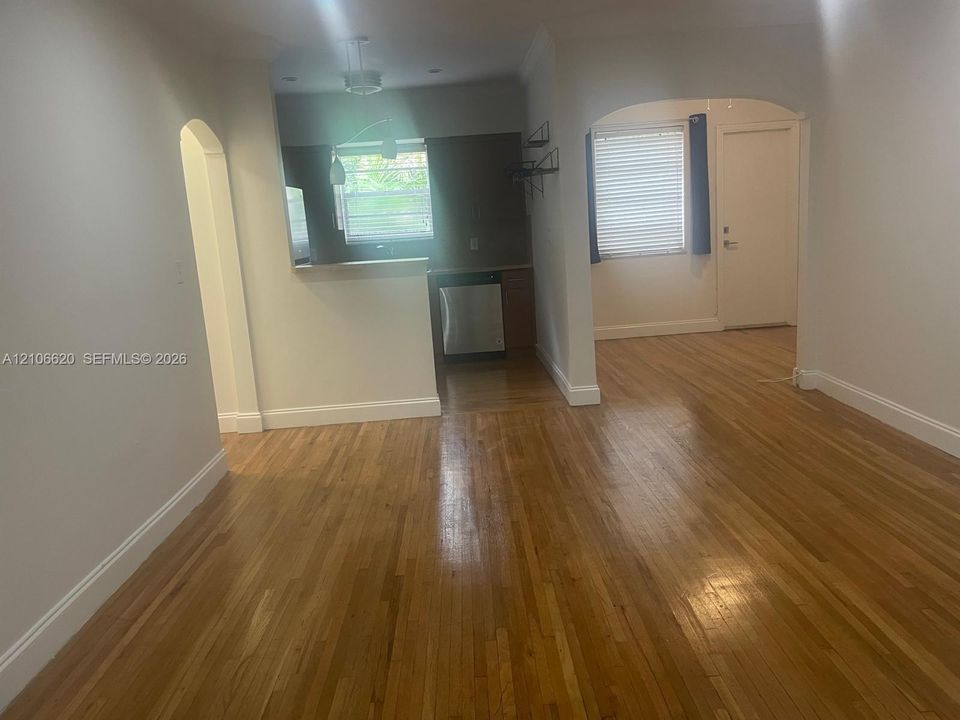 Interior featuring wood-finish flooring, arched entryways, and kitchen with stainless steel dishwasher and pass-through counter