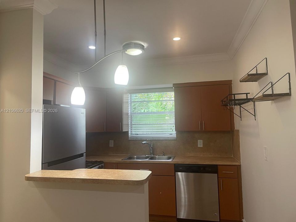 Kitchen featuring wood cabinetry, stainless steel appliances, a dual-basin sink, and crown molding