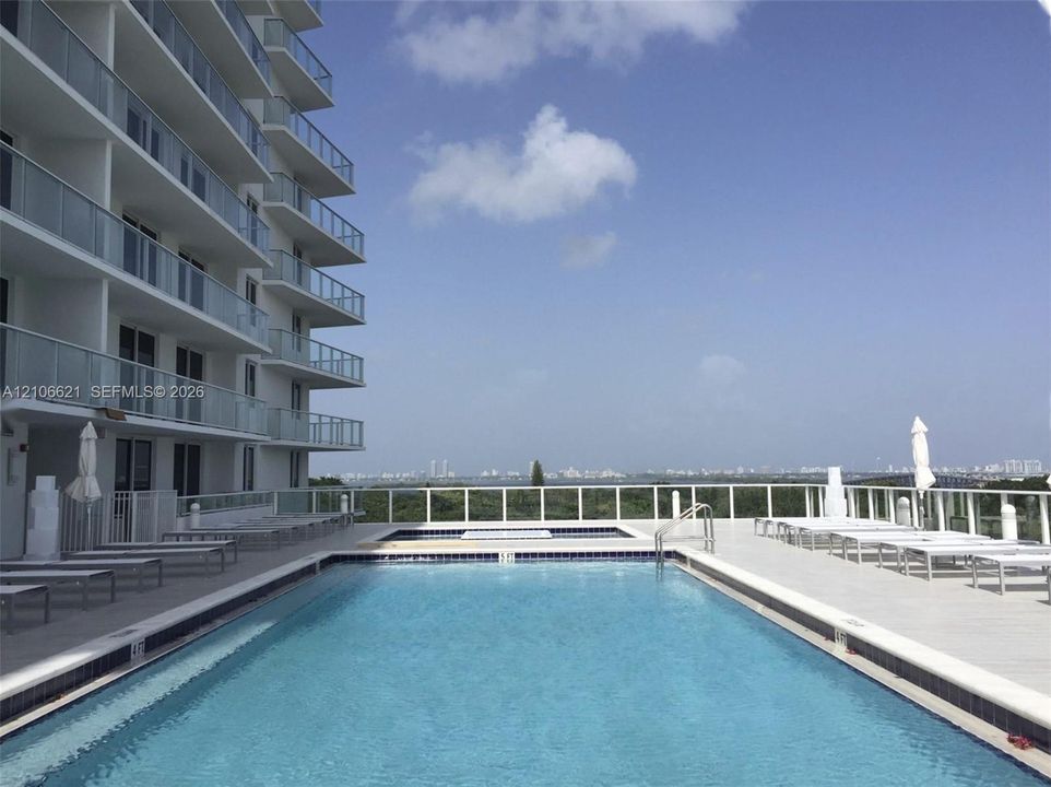 Swimming pool with tiled perimeter, integrated spa, and concrete deck enclosed by metal railing