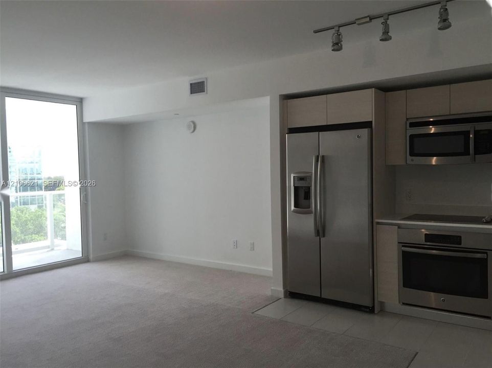 Kitchen featuring flat-panel cabinetry, stainless steel appliances, and integrated track lighting, complemented by a floor-to-ceiling glass door
