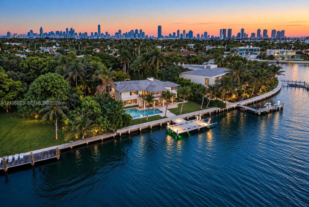 Waterfront property featuring a private dock, swimming pool, manicured lawn, and mature landscaping with a city skyline backdrop