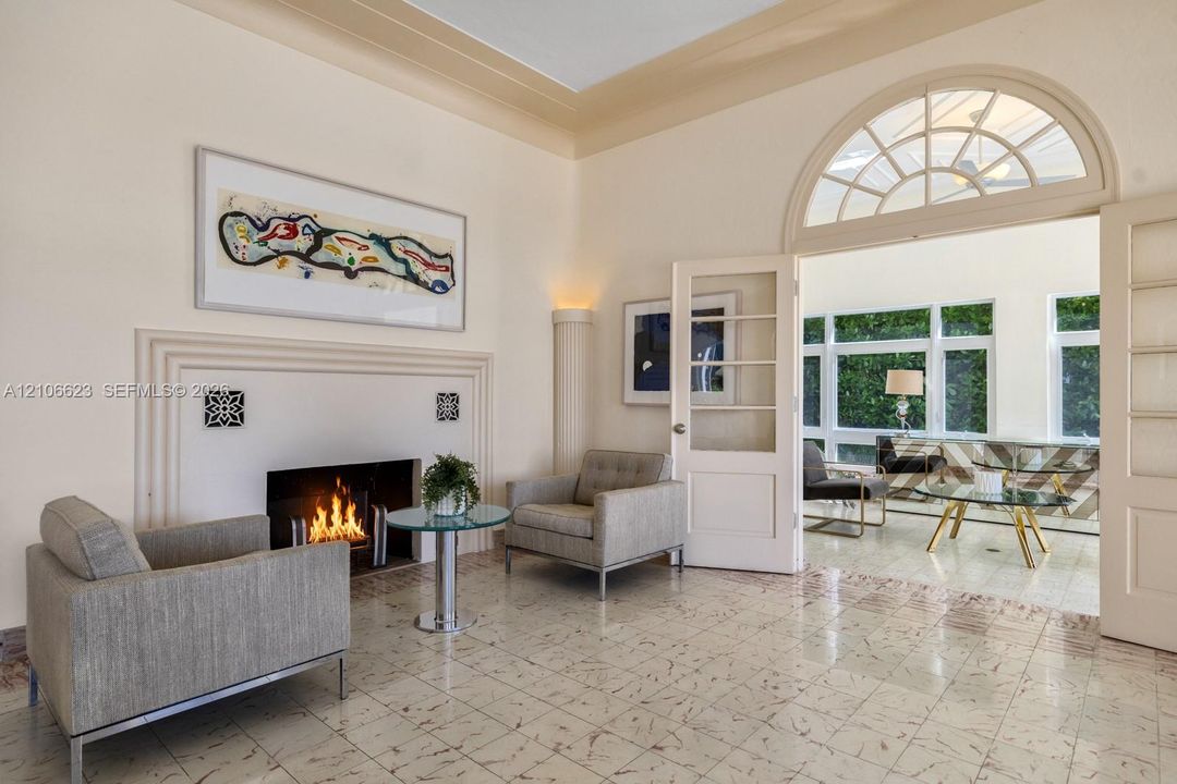 Fireplace with custom molding, high-gloss tile flooring, arched fanlight transom window, glass-paned French doors, and elevated tray ceilings