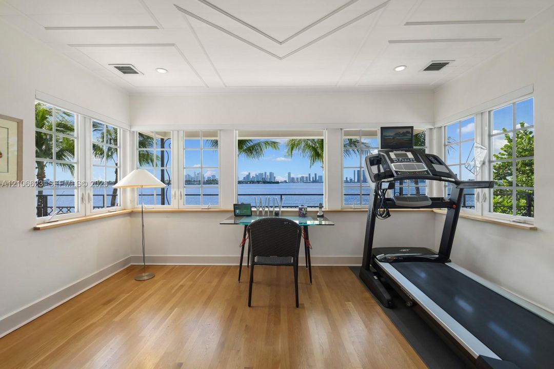 Multi-pane windows, wood-finish flooring, recessed lighting, and geometric coffered ceiling detail, with expansive water and skyline exposure