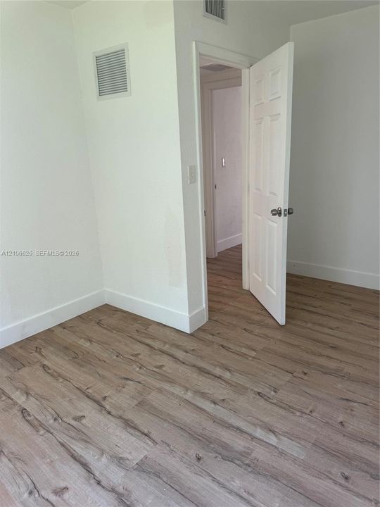 Neutral wall color, wood-finish flooring, and six-panel interior door