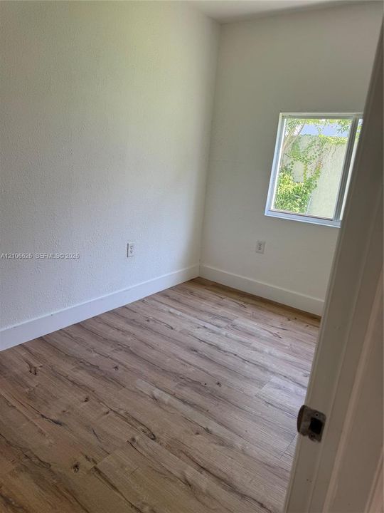 Interior space featuring wood-finish flooring, neutral walls, and a single-pane window