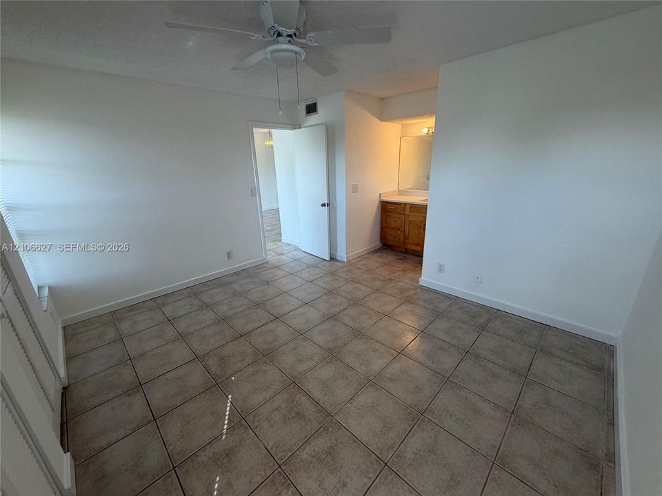Room featuring neutral ceramic tile flooring, a white ceiling fan, and a built-in vanity cabinet with a rectangular mirror