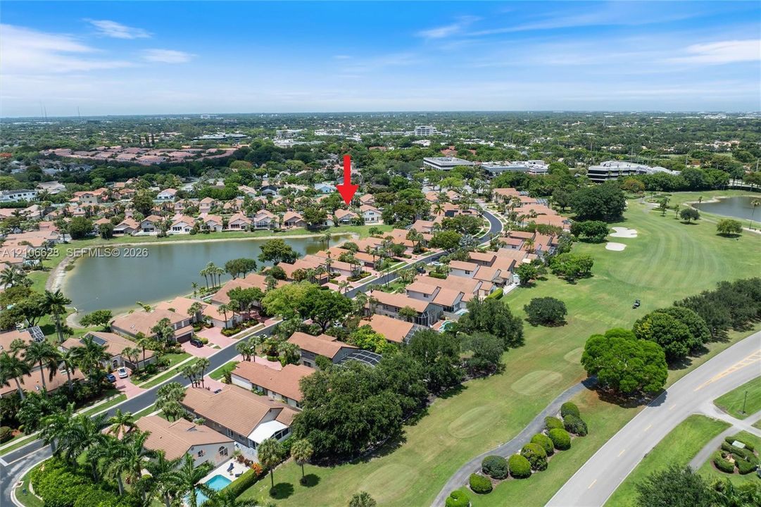 Aerial perspective of residential property featuring tile roof construction, proximity to a lake, mature landscaping, and integration into a golf course community