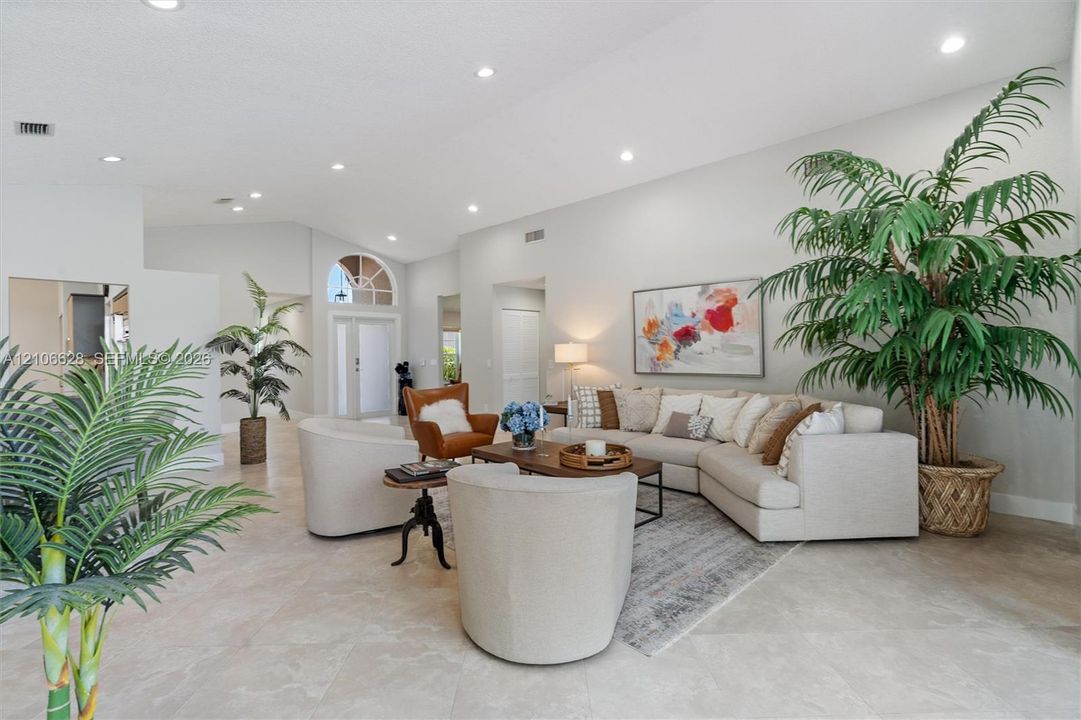 Vaulted ceilings, neutral tile flooring, recessed lighting, and an arched transom window above the entrance door