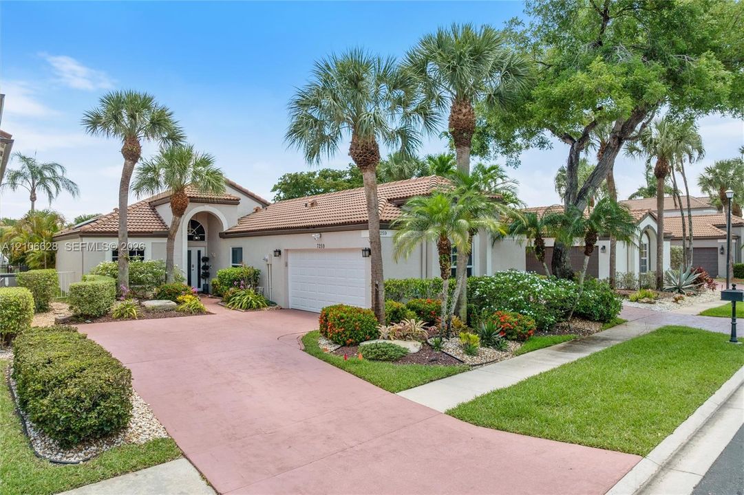 Single-story exterior featuring a tile roof, multi-car garage, arched entryway, and landscaped grounds with mature palm trees