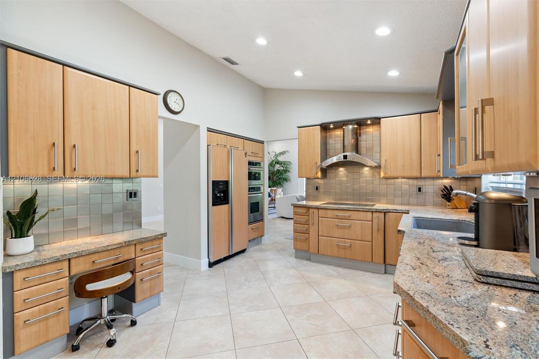 Kitchen featuring light-tone cabinetry, stone countertops, square-tile backsplash, stainless steel appliances, and vaulted ceilings with recessed lighting
