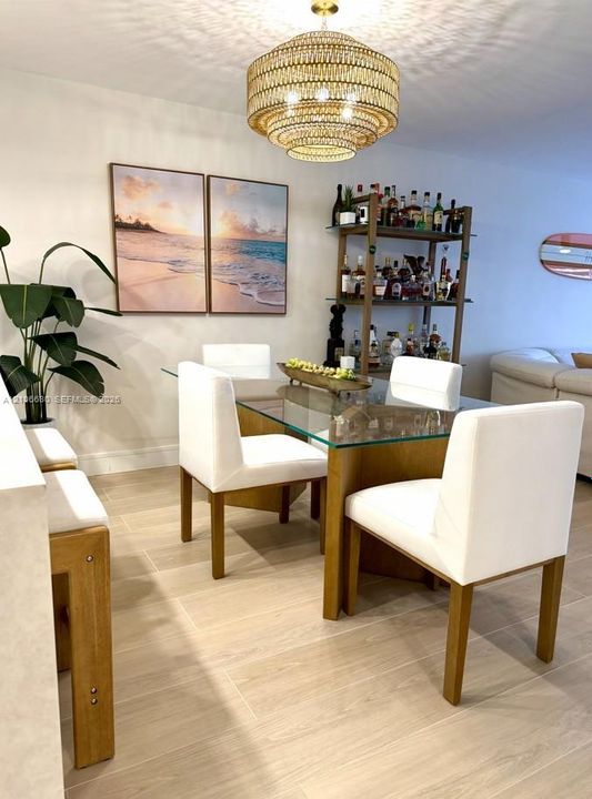 Elegant dining space featuring a wood-base dining table with glass top, upholstered dining chairs in cream fabric, and wide-plank wood-finish flooring