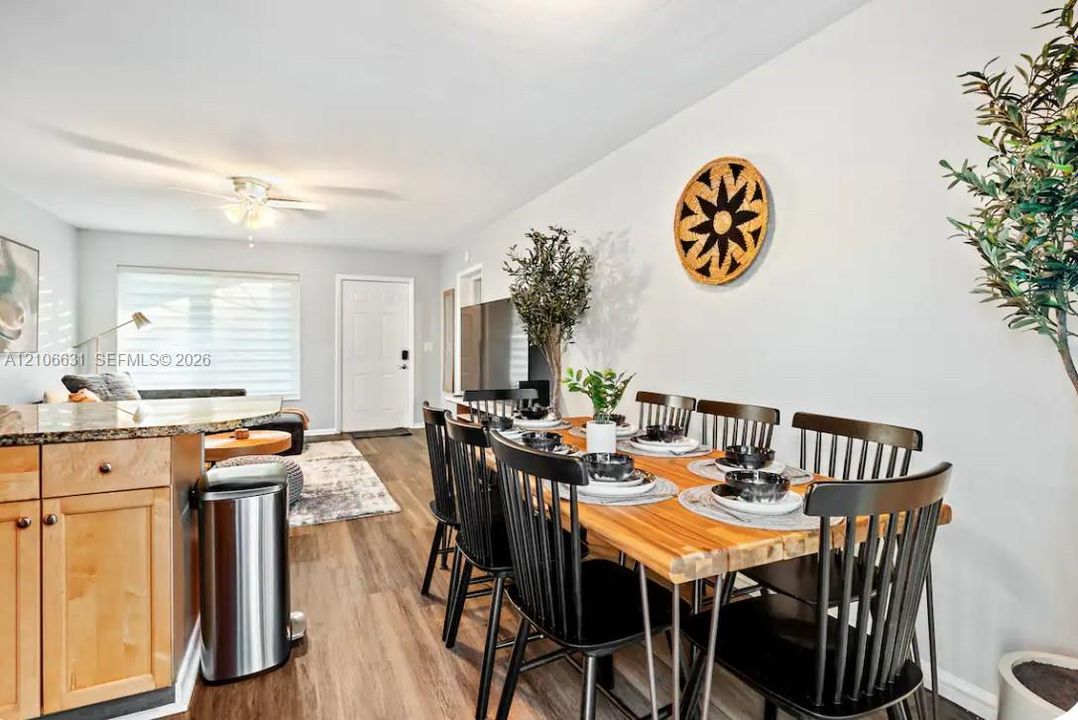 Open-concept interior featuring light wood-finish flooring, wood cabinetry with stone-finish countertops, and a ceiling fan