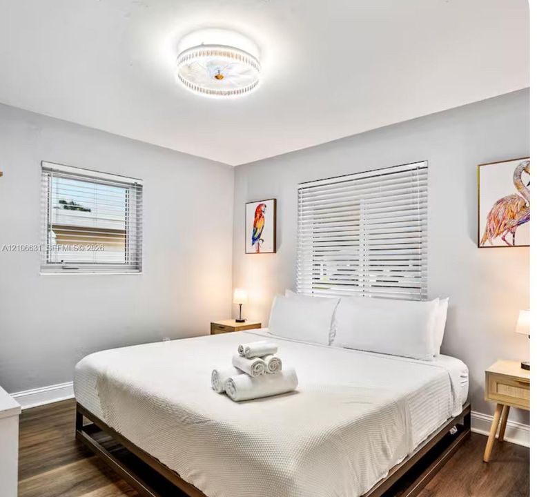 Room featuring wood-finish flooring, dual windows with horizontal blinds, and a circular flush-mount ceiling fixture