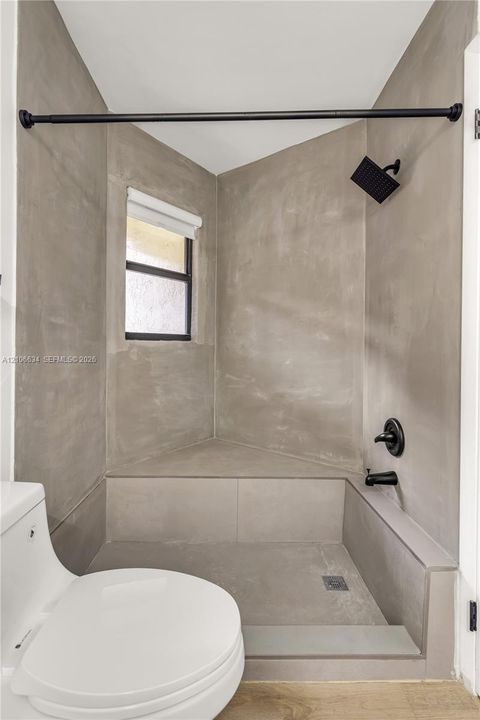Walk-in shower, a built-in bench, matte black rainfall showerhead, and matte black fixtures