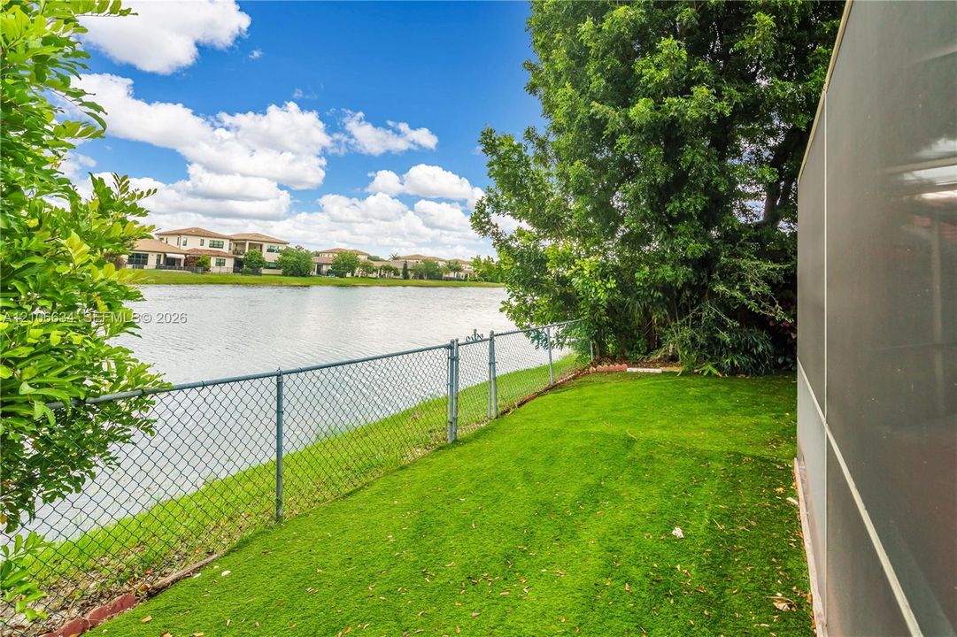 Space between screened outdoor screened patio area and gate leading to lake access has turf for low-maintenance