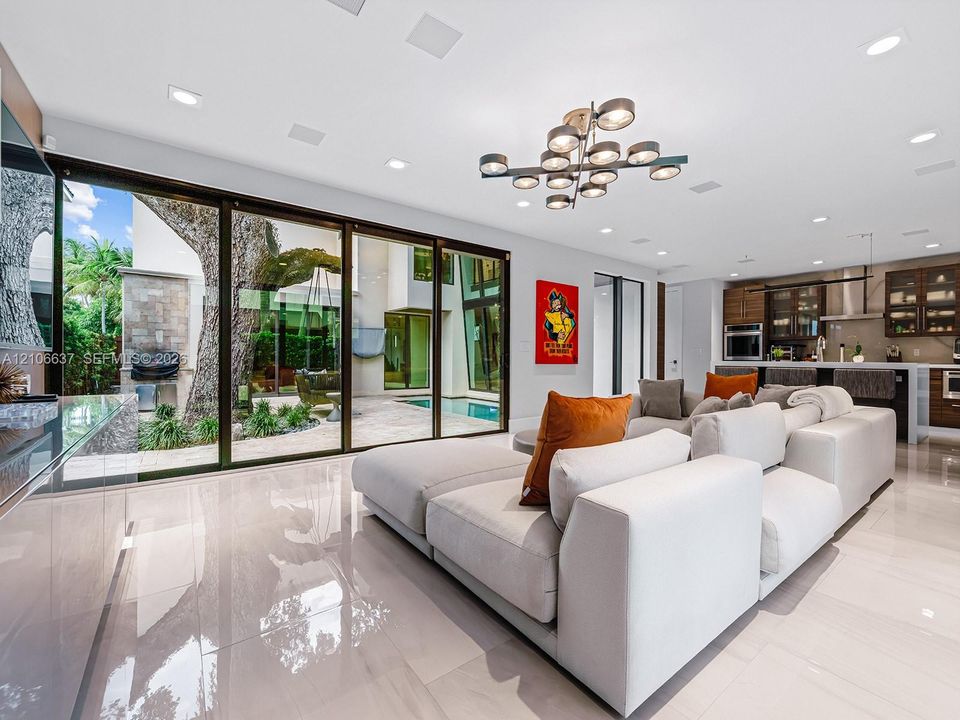 Large-format sliding glass doors, polished porcelain tile flooring, multi-light contemporary chandelier, and recessed ceiling lighting