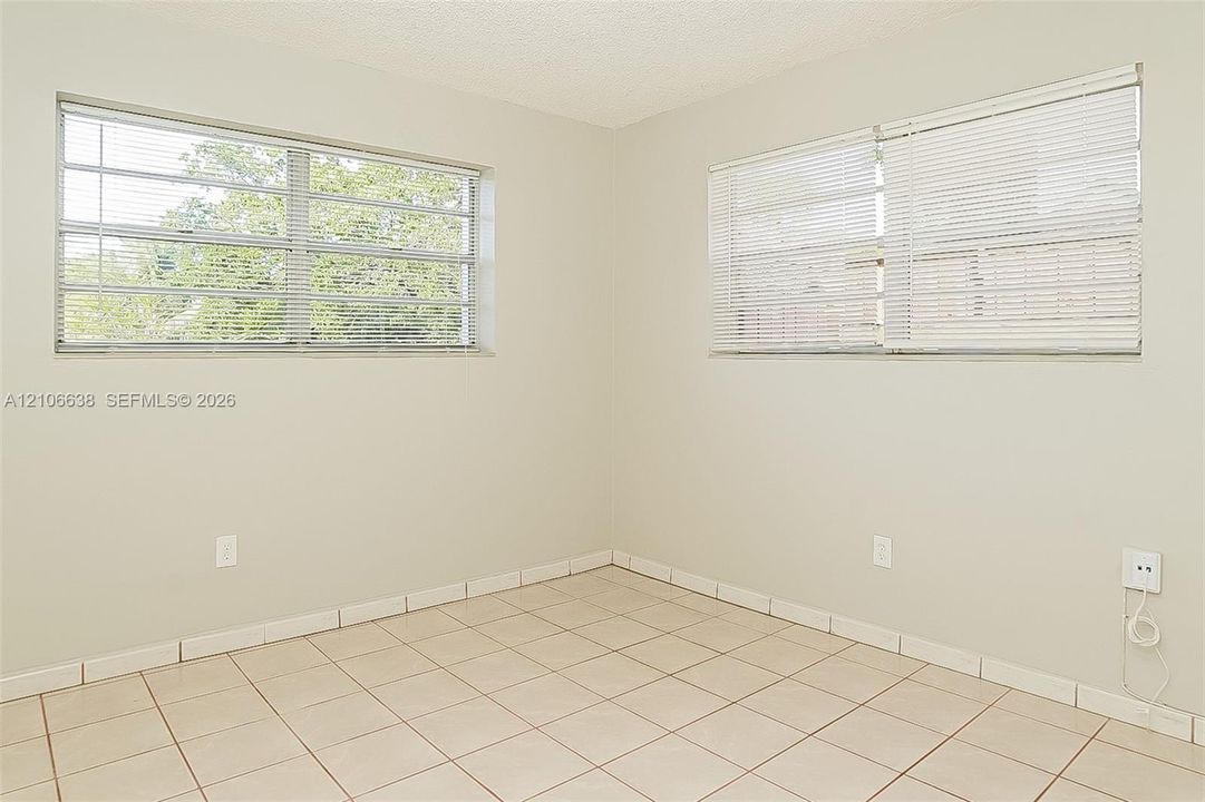 Neutral-toned interior space featuring large multi-pane windows and light-colored ceramic tile flooring