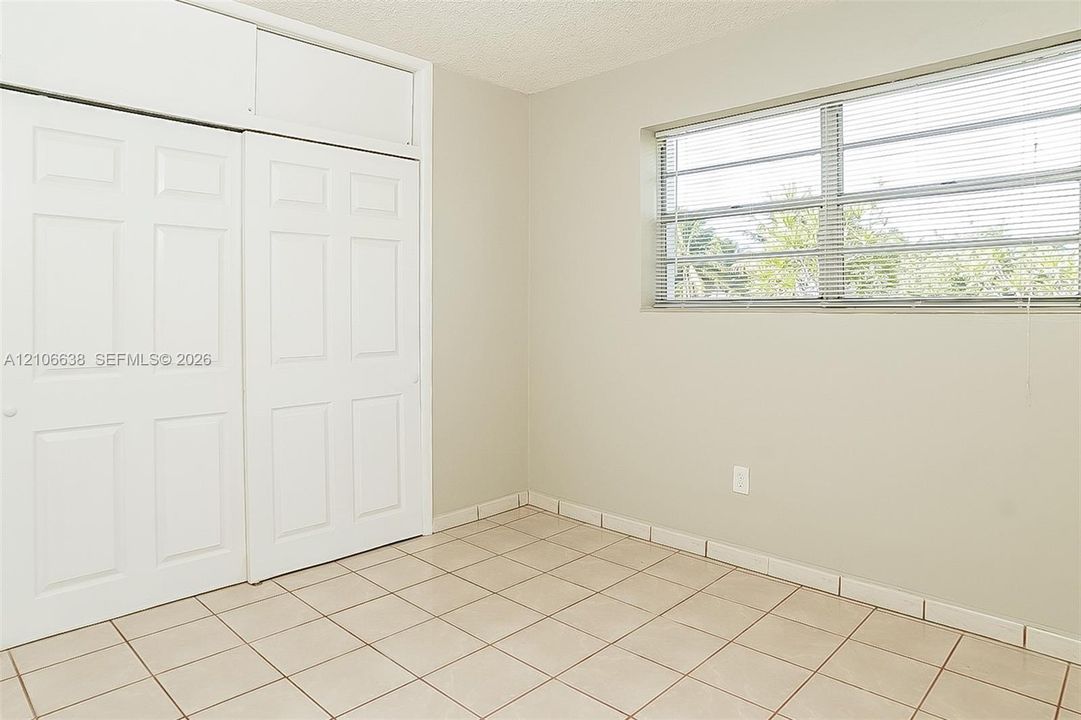 Interior space featuring tile flooring, neutral wall paint, and floor-to-ceiling closet cabinetry with overhead storage compartments