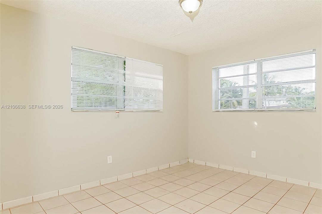 Neutral-toned interior featuring ceramic tile flooring, dual louvered-style windows, and a central ceiling-mounted light fixture