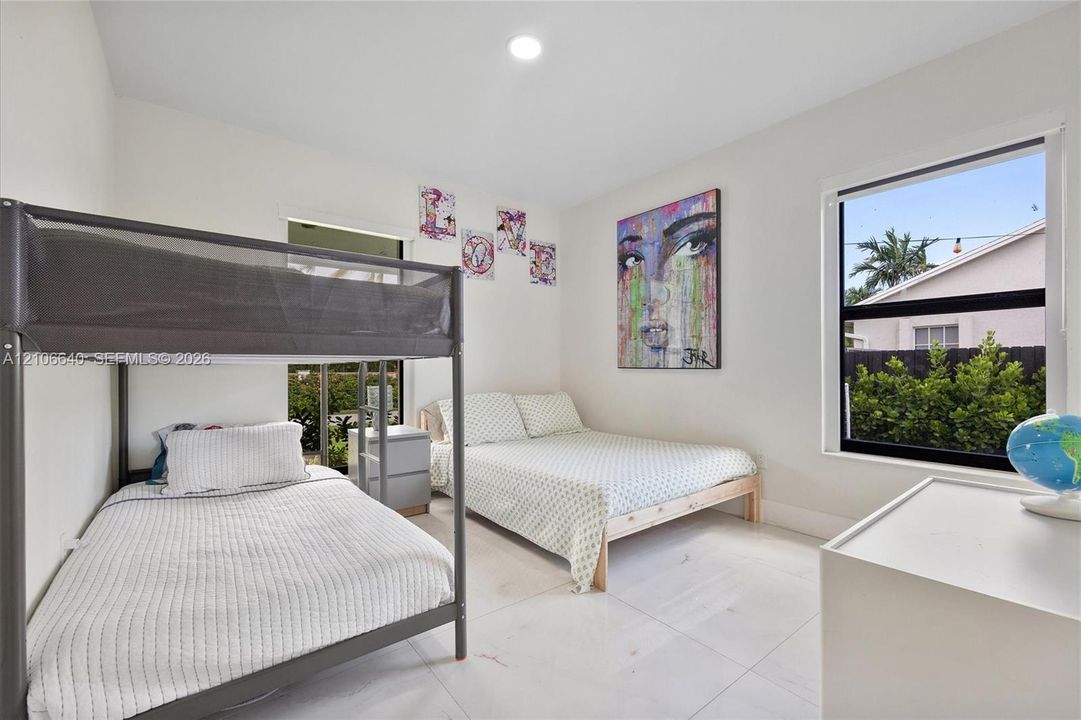 Recessed lighting, large window with exterior landscaping, light tile flooring, white walls, and a built-in window