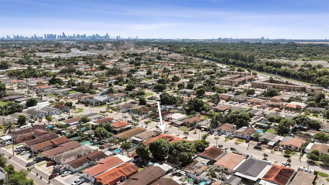 Aerial perspective of residential property featuring a clay tile roof, mature canopy trees, and established landscaping