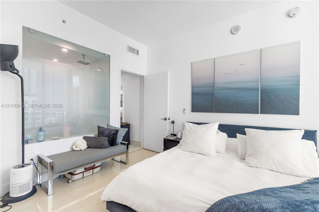Room featuring polished tile flooring, a floor-to-ceiling glass wall panel, and smooth, neutral-toned wall surfaces