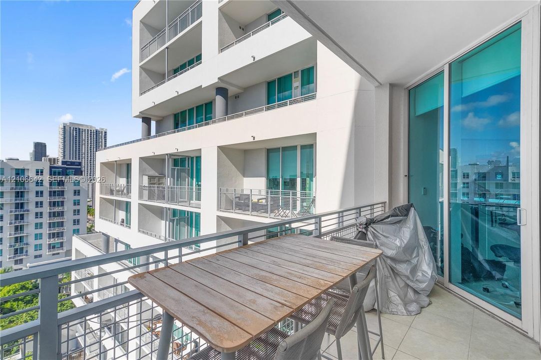 Covered balcony featuring concrete flooring, metal railing, and floor-to-ceiling glass sliding doors
