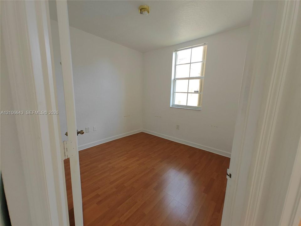 Room featuring wood-finish flooring, white walls, and a closet with bifold doors