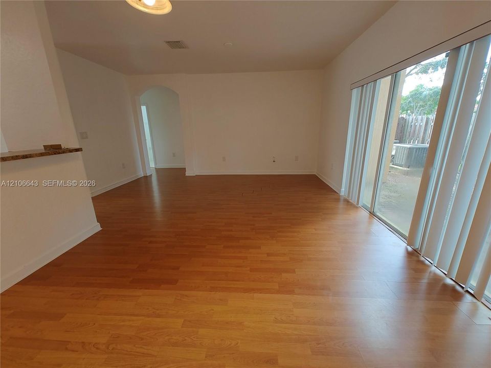Interior space featuring wood-finish flooring, a multi-light metal chandelier, and a sliding glass door with vertical blinds