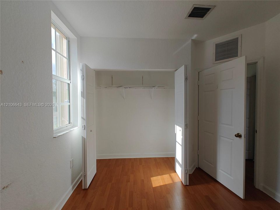Room featuring wood-finish flooring, white walls, and a window with a multi-pane grid