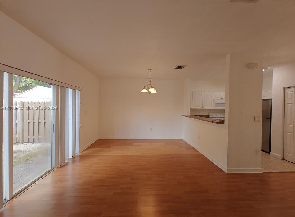 Interior space featuring wood-finish flooring, a neutral color palette, an arched doorway, and large glass sliding doors