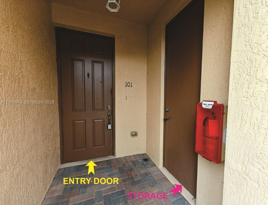 Entryway featuring a four-panel door with a classic peephole, metal lever handle hardware, and a textured stucco exterior finish