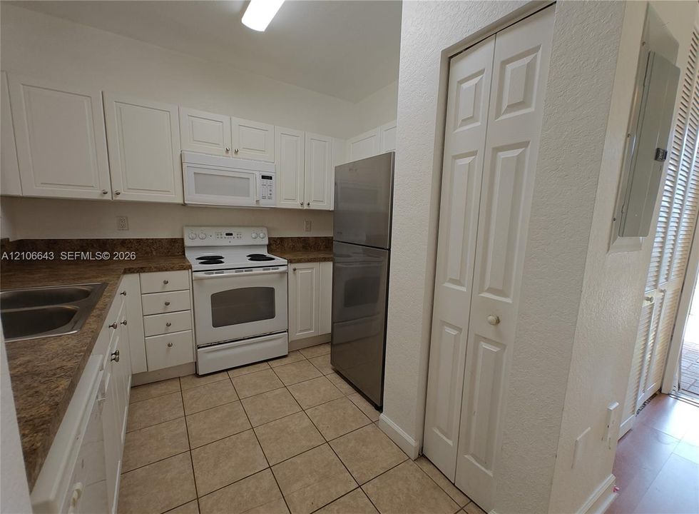 Kitchen featuring white cabinetry, stone-finish countertops, stainless steel refrigerator, and wood-finish flooring