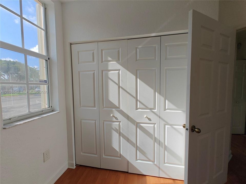 Wood-finish flooring, multi-pane window, built-in closet with shelving, and interior panel doors