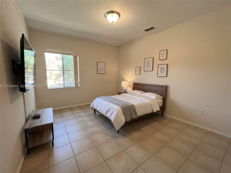 Neutral-toned room featuring large-format ceramic tile flooring, a dual-pane window, and a flush-mount ceiling light fixture