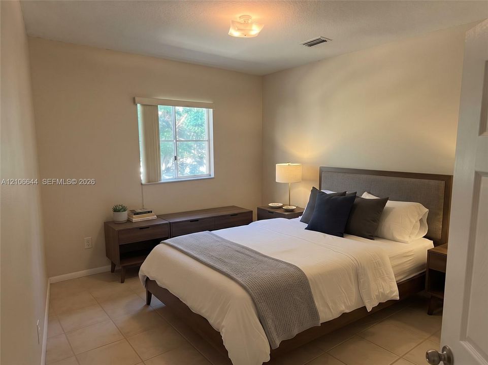 Neutral-toned walls, tile flooring, and a single-pane window with horizontal blinds