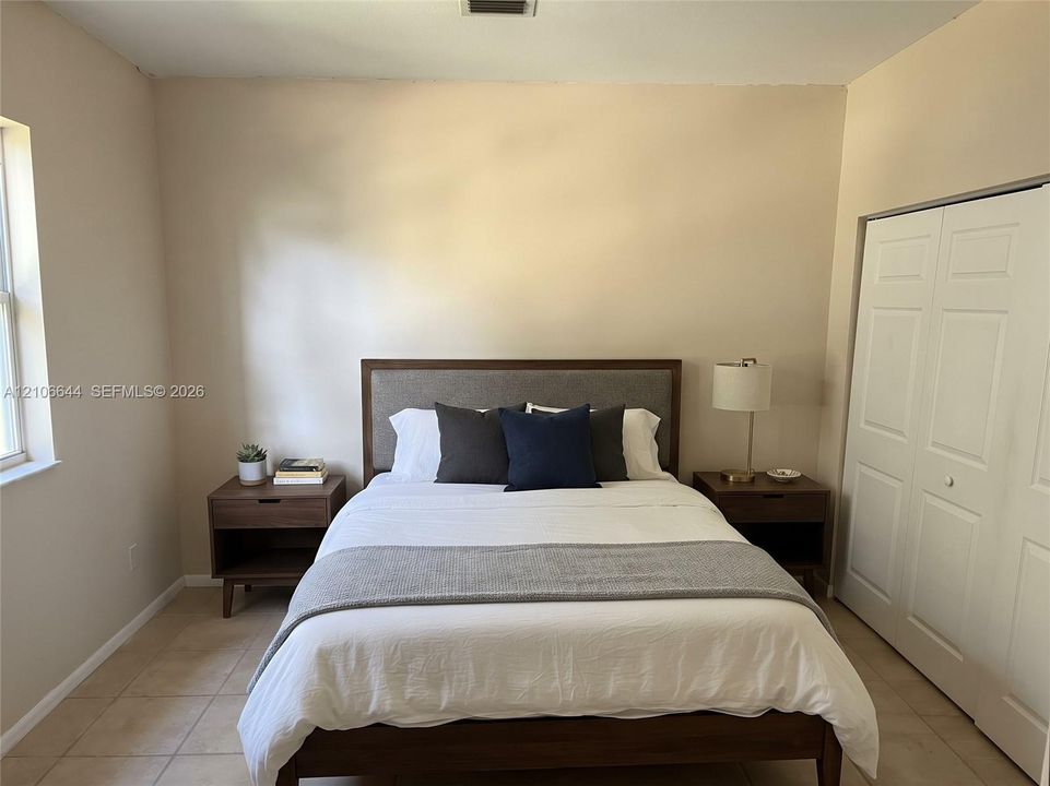 Neutral-toned interior featuring ceramic tile flooring, a large window, and a white bi-fold closet door