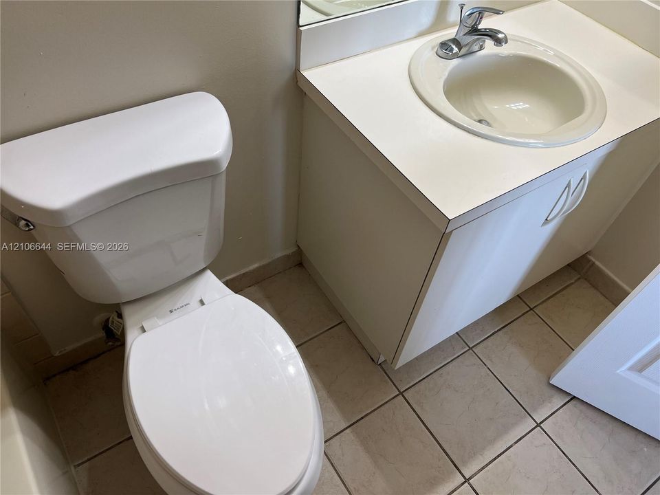 Bathroom featuring a vanity with an integrated sink and chrome faucet, solid-surface countertop, and ceramic tile flooring