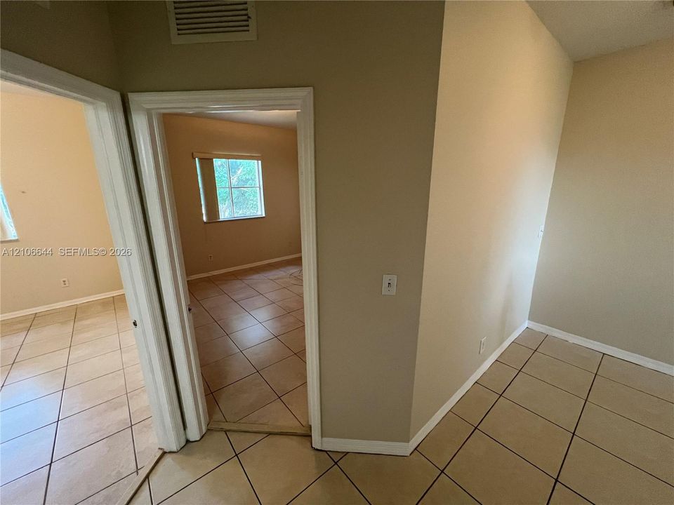 Neutral-toned interior featuring ceramic tile flooring, solid core doors with white trim, and a multi-pane window