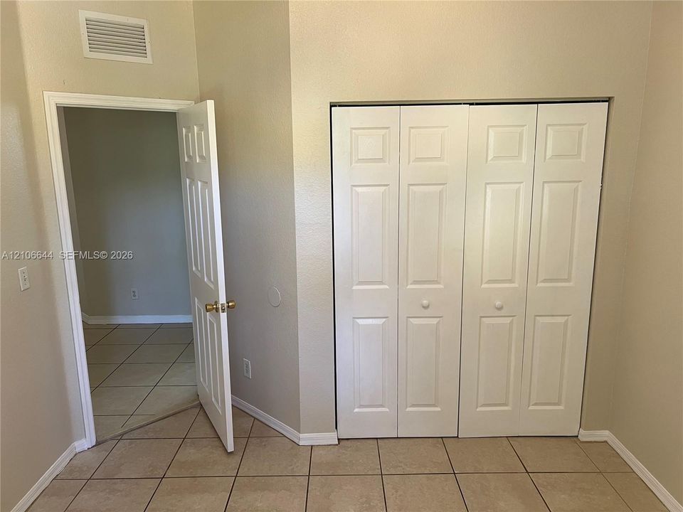 Ceramic tile flooring, white bi-fold closet doors, and interior door with brass-finish hardware