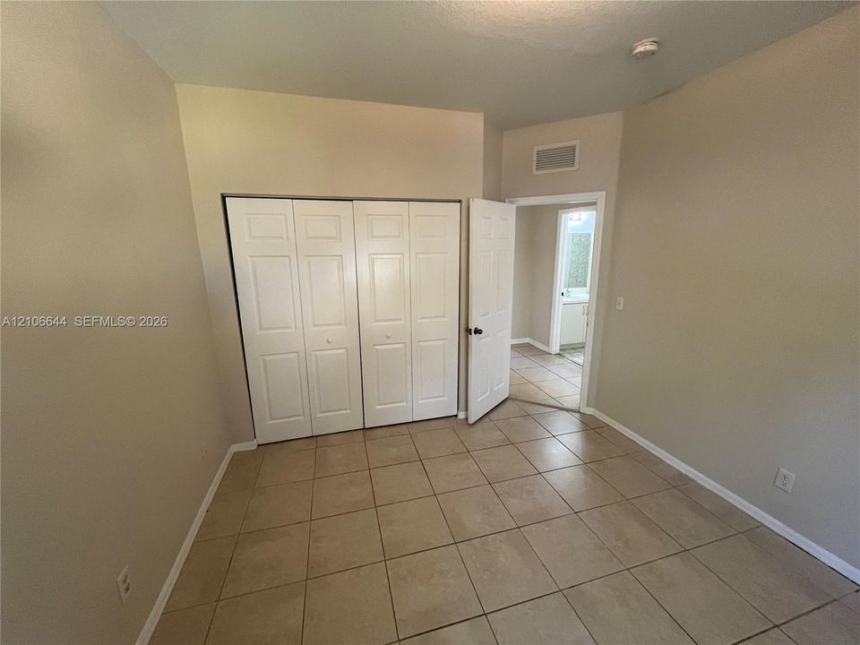 Interior space featuring neutral wall paint, tile flooring, and a multi-panel closet with white doors